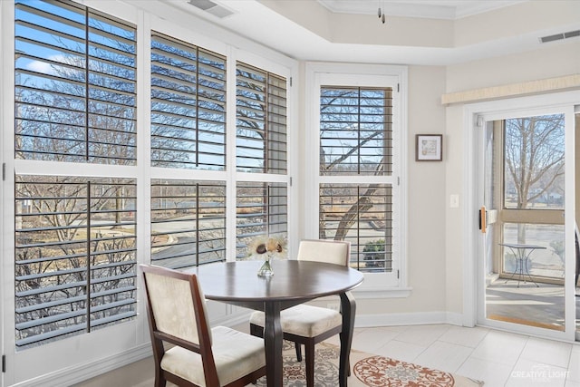 tiled dining space with crown molding, a wealth of natural light, and a tray ceiling