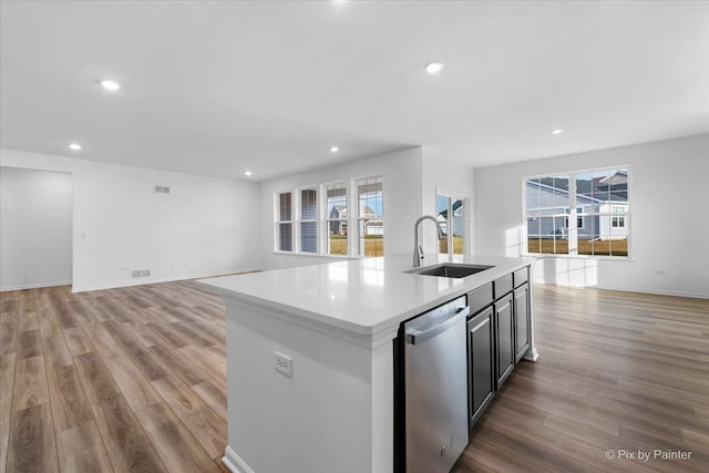 kitchen featuring sink, dishwasher, a kitchen island with sink, and light hardwood / wood-style flooring