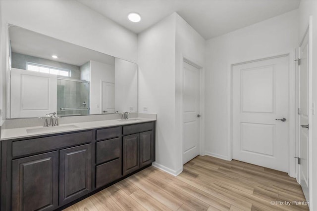 bathroom with a shower with door, wood-type flooring, and vanity