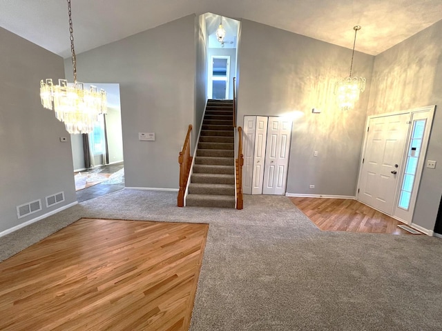 foyer entrance featuring carpet flooring, high vaulted ceiling, and a notable chandelier