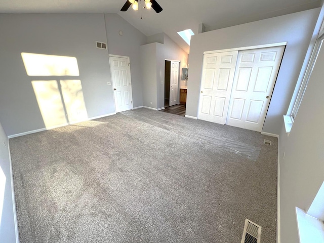 unfurnished bedroom with connected bathroom, dark colored carpet, vaulted ceiling, a closet, and ceiling fan