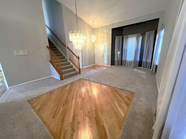 foyer with vaulted ceiling, carpet flooring, and a notable chandelier