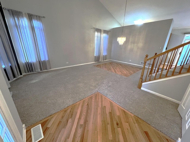 carpeted foyer entrance with an inviting chandelier and vaulted ceiling