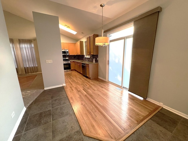 kitchen with tasteful backsplash, lofted ceiling, appliances with stainless steel finishes, and decorative light fixtures