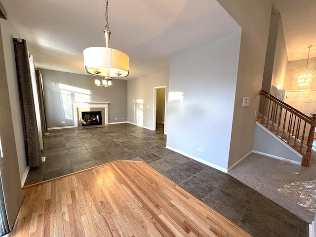 unfurnished living room featuring an inviting chandelier and dark hardwood / wood-style flooring