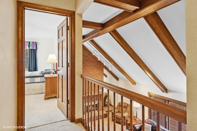 hallway with vaulted ceiling with beams and light colored carpet