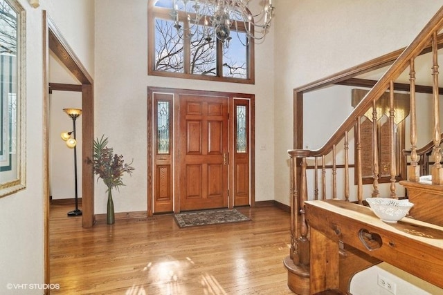 foyer featuring a towering ceiling, hardwood / wood-style floors, and a notable chandelier