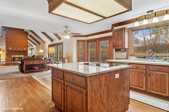 kitchen with lofted ceiling with beams, a brick fireplace, a center island, and a wealth of natural light