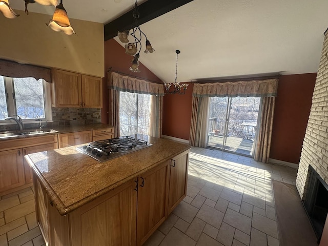 kitchen with sink, decorative backsplash, a kitchen island, decorative light fixtures, and stainless steel gas stovetop