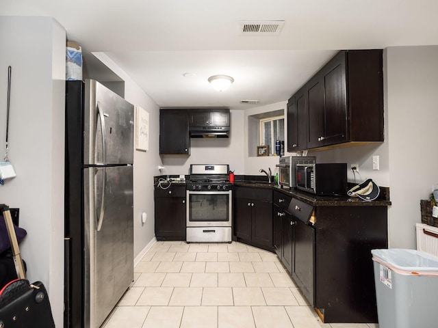 kitchen with appliances with stainless steel finishes, sink, light tile patterned floors, and dark brown cabinetry