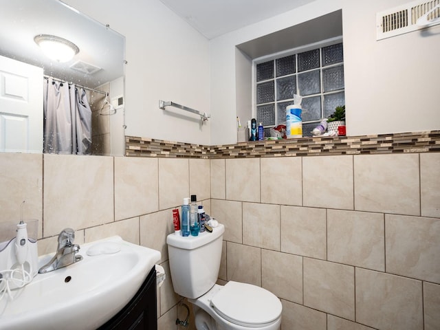 bathroom with vanity, tile walls, toilet, and a shower with shower curtain