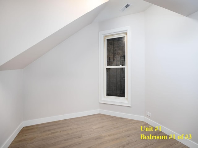 bonus room with lofted ceiling and light wood-type flooring