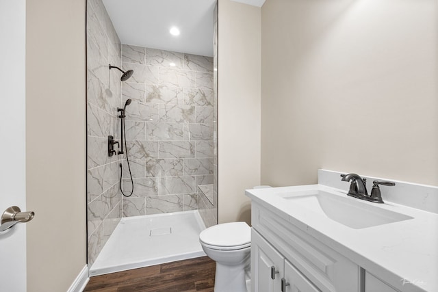 bathroom featuring tiled shower, vanity, toilet, and hardwood / wood-style floors