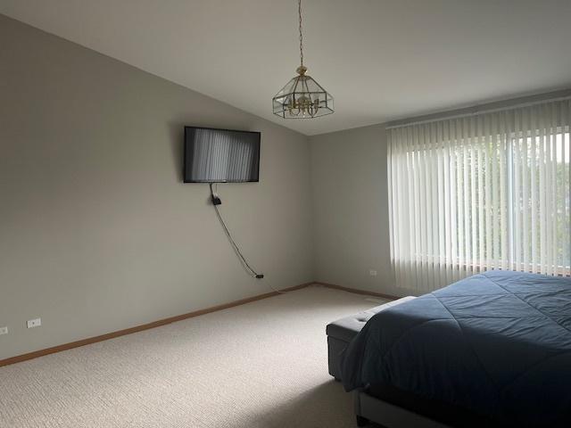 bedroom featuring an inviting chandelier, vaulted ceiling, and carpet