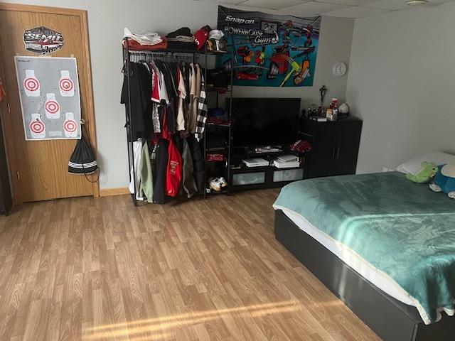 bedroom with a drop ceiling and wood-type flooring