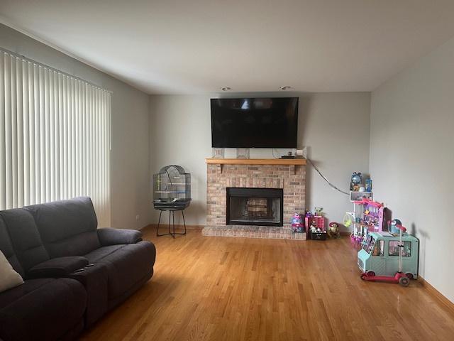 living room with hardwood / wood-style floors and a brick fireplace