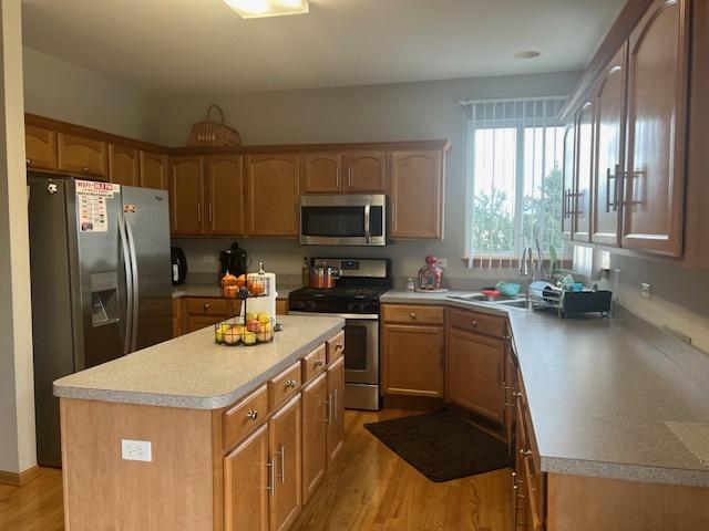 kitchen featuring appliances with stainless steel finishes, a center island, sink, and light hardwood / wood-style floors