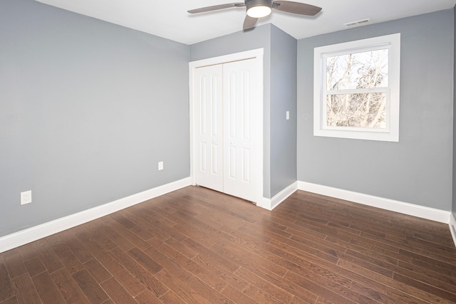 unfurnished bedroom featuring dark hardwood / wood-style floors, ceiling fan, and a closet