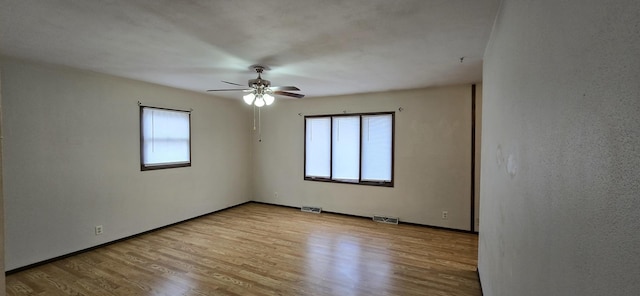 spare room with light wood-style floors, visible vents, and a healthy amount of sunlight