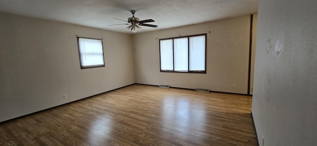 spare room featuring light wood-type flooring, baseboards, visible vents, and a ceiling fan