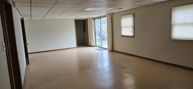 spare room with light floors, baseboards, and a drop ceiling