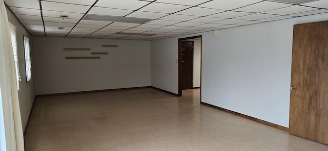 unfurnished room featuring light speckled floor, a paneled ceiling, and baseboards