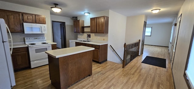 kitchen with a center island, light countertops, a sink, light wood-type flooring, and white appliances