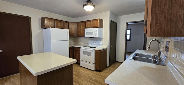 kitchen featuring white appliances, decorative backsplash, light wood-style flooring, light countertops, and a sink