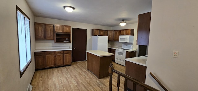 kitchen with white appliances, a kitchen island, light countertops, dark brown cabinets, and light wood-type flooring