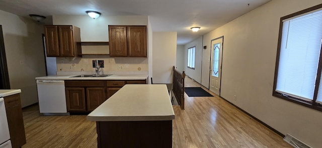 kitchen featuring light countertops, visible vents, a kitchen island, a sink, and dishwasher