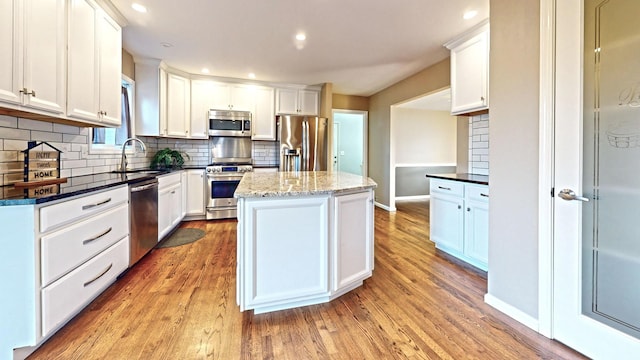 kitchen with white cabinetry, appliances with stainless steel finishes, sink, and a center island