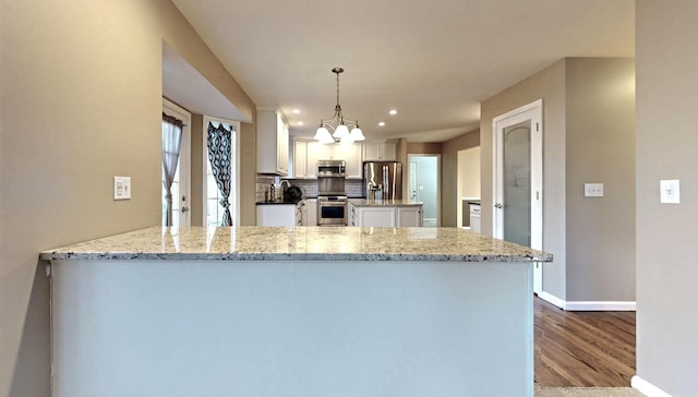 kitchen featuring white cabinetry, light stone counters, an inviting chandelier, hanging light fixtures, and appliances with stainless steel finishes