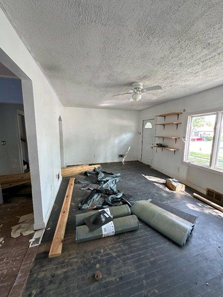 unfurnished living room featuring ceiling fan and a textured ceiling