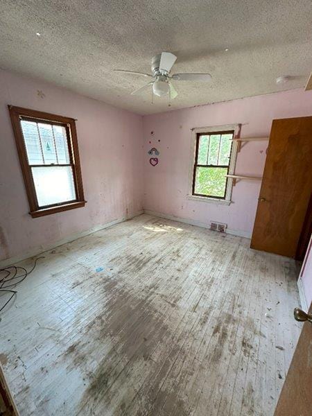 unfurnished room featuring ceiling fan, a textured ceiling, and light wood-type flooring