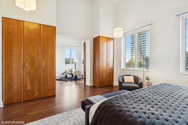 bedroom with a towering ceiling and dark hardwood / wood-style floors