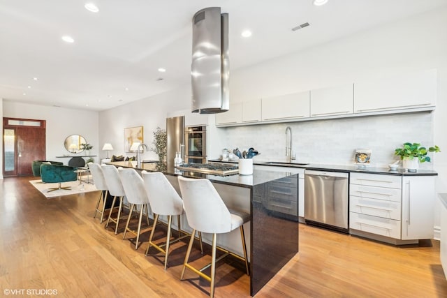 kitchen with sink, an island with sink, white cabinets, and appliances with stainless steel finishes