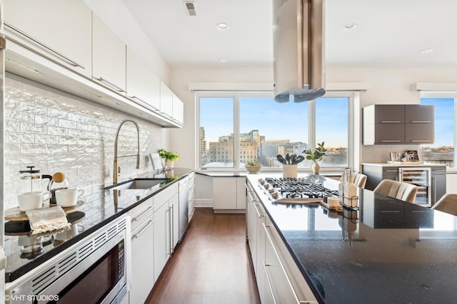 kitchen featuring wine cooler, sink, white cabinetry, tasteful backsplash, and appliances with stainless steel finishes