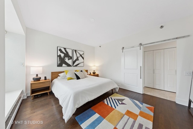 bedroom featuring dark wood-type flooring, a barn door, and a closet