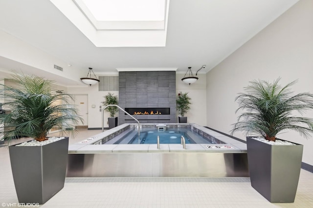 view of swimming pool featuring a skylight, a fireplace, and an indoor in ground hot tub