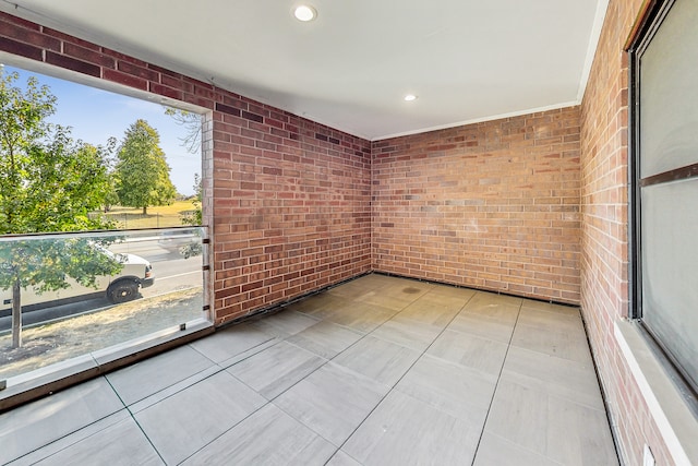 spare room with light tile patterned flooring and brick wall