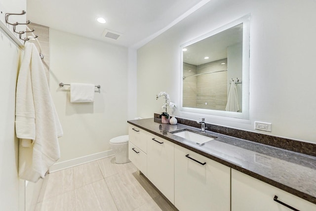 bathroom with tiled shower, vanity, toilet, and tile patterned floors