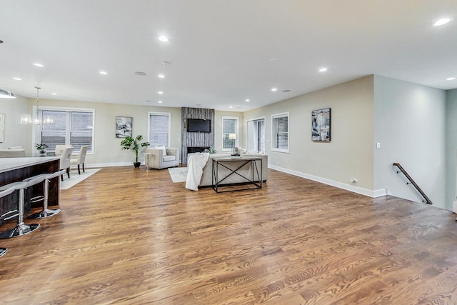 living room with an inviting chandelier, wood-type flooring, and a large fireplace