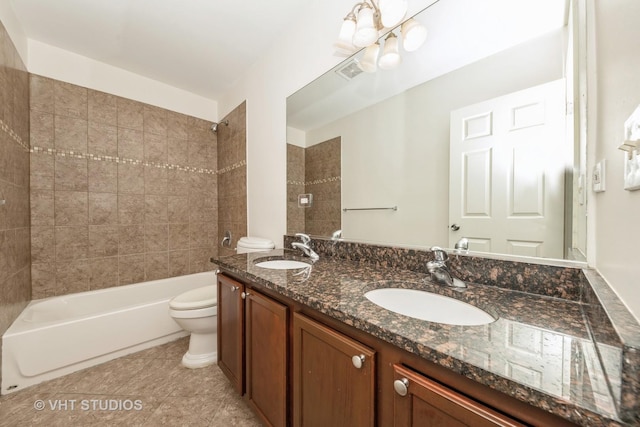 full bathroom with tile patterned flooring, vanity, tiled shower / bath combo, and toilet