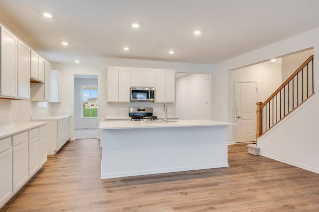 kitchen with white cabinetry, sink, stainless steel appliances, and a center island with sink