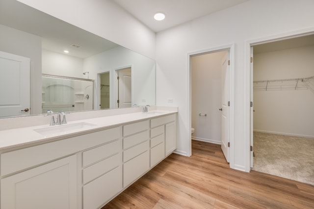 bathroom featuring vanity, wood-type flooring, a shower with shower door, and toilet