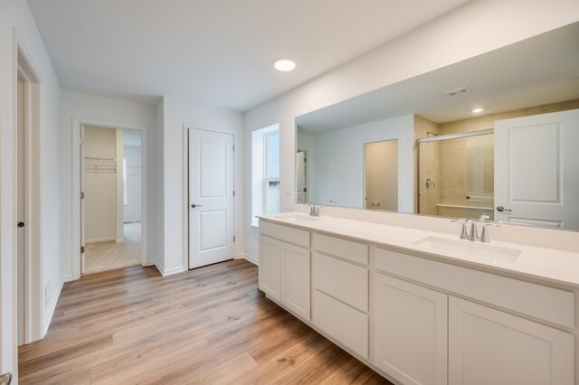 bathroom with vanity, a shower with shower door, and hardwood / wood-style floors