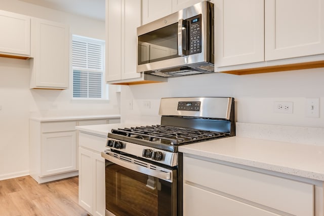 kitchen featuring light stone counters, stainless steel appliances, light hardwood / wood-style flooring, and white cabinets