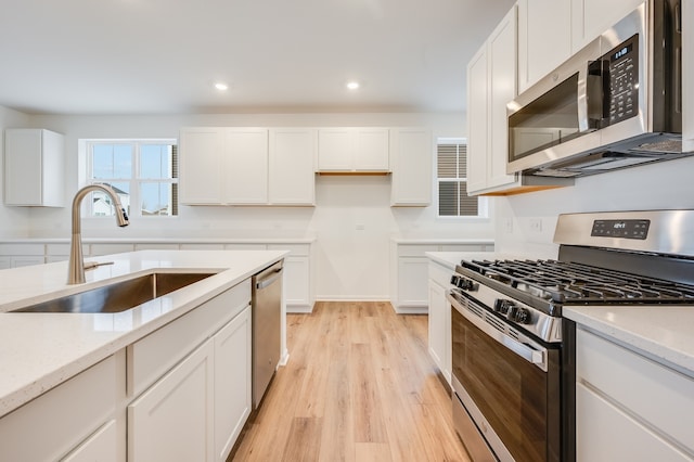 kitchen featuring white cabinetry, appliances with stainless steel finishes, light stone countertops, and sink