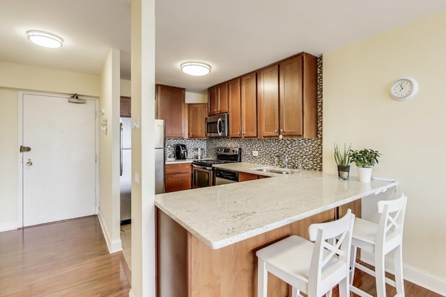 kitchen with appliances with stainless steel finishes, a kitchen breakfast bar, sink, and backsplash