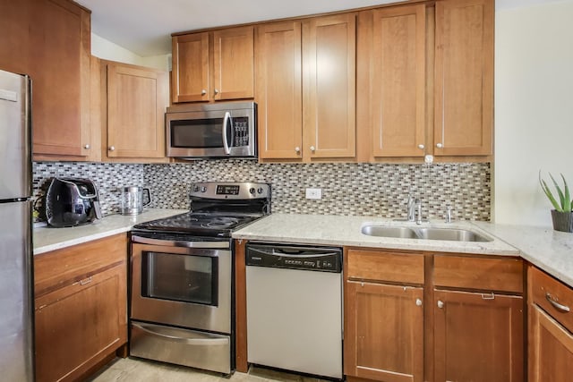 kitchen with tasteful backsplash, sink, light stone countertops, and appliances with stainless steel finishes